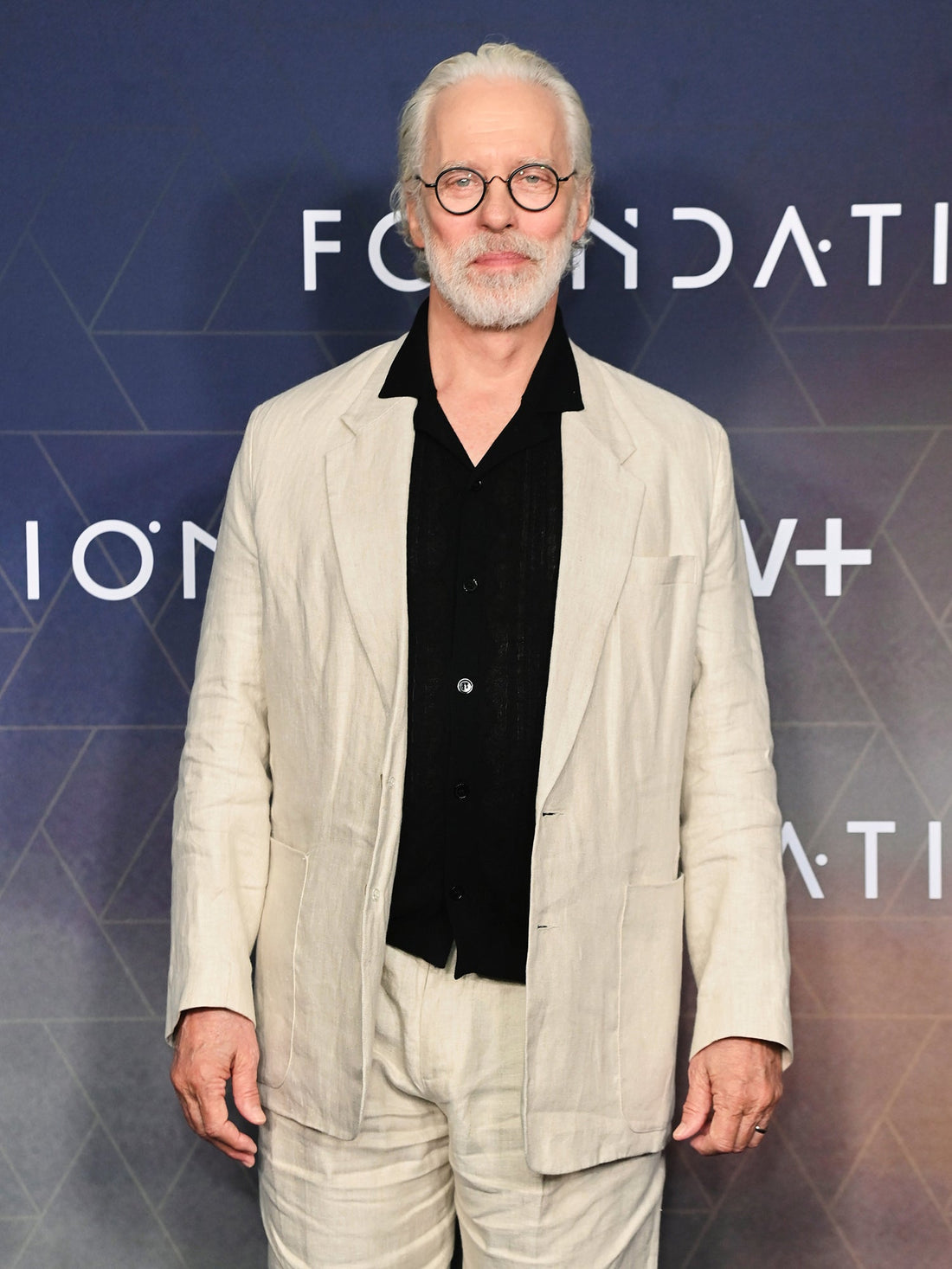 Actor Terrence Mann wearing Heron’s Ghyll beige linen suit with black shirt at the Foundation photocall in London