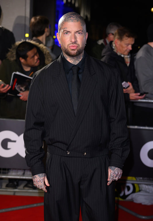 Jamie Lloyd on the red carpet at the GQ Men of the Year Awards 2025 in London, wearing the Heron’s Ghyll Rico Cropped Suit in black with a grey chalk stripe.