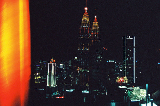 The Petronas Twin Towers lit up at night, seen from a rooftop