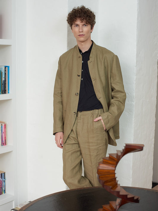Brown linen stand collar jacket on a model leaning against the wall