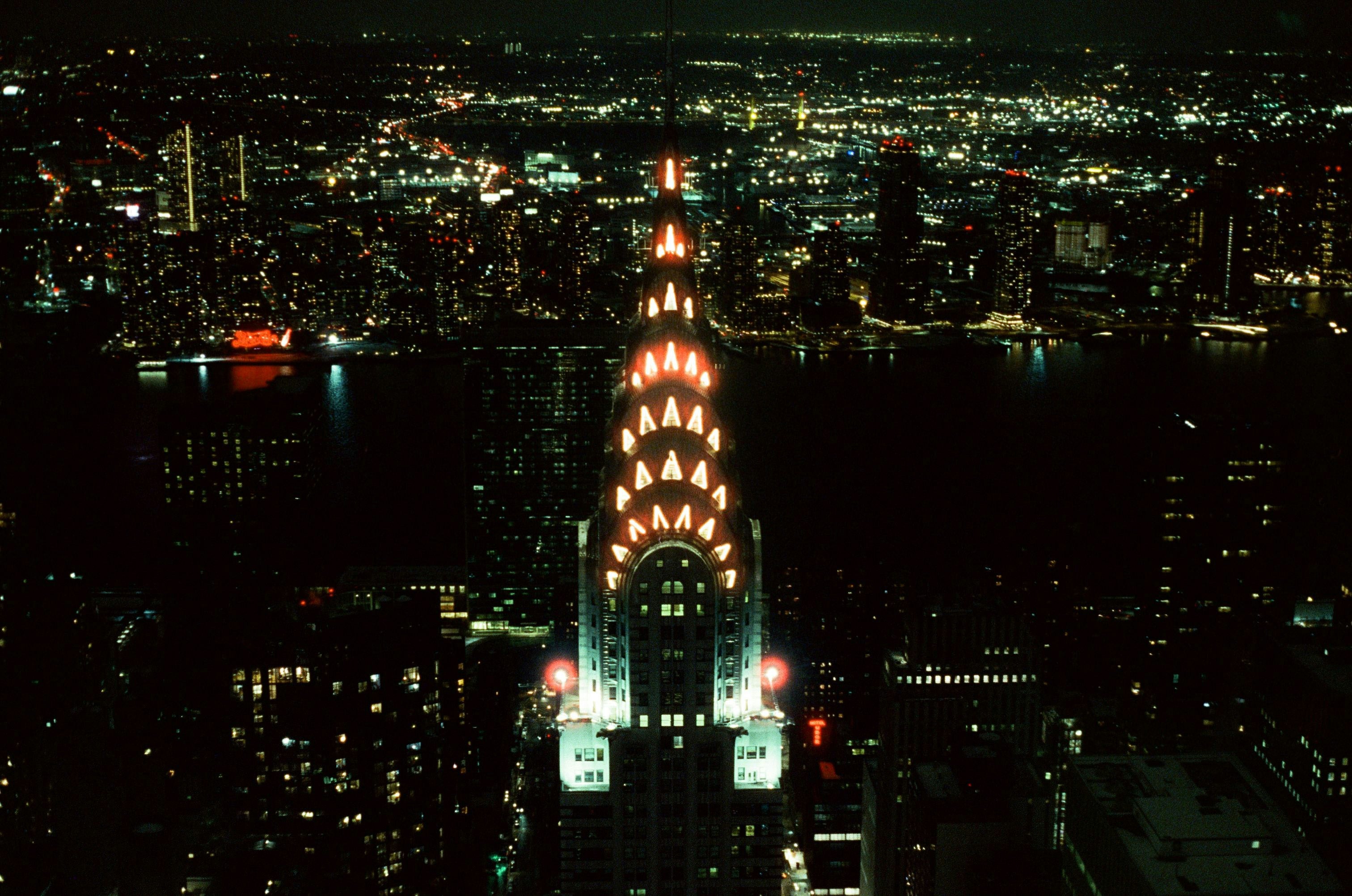 Film photo of NYC at night, aerial view of the Chrysler Building top, atmospheric, looking towards Brooklyn.