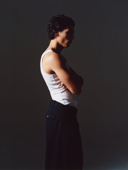 Side view of man in shadow wearing the Lavelle inverted pleat trousers, arms crossed, showing the higher back rise.